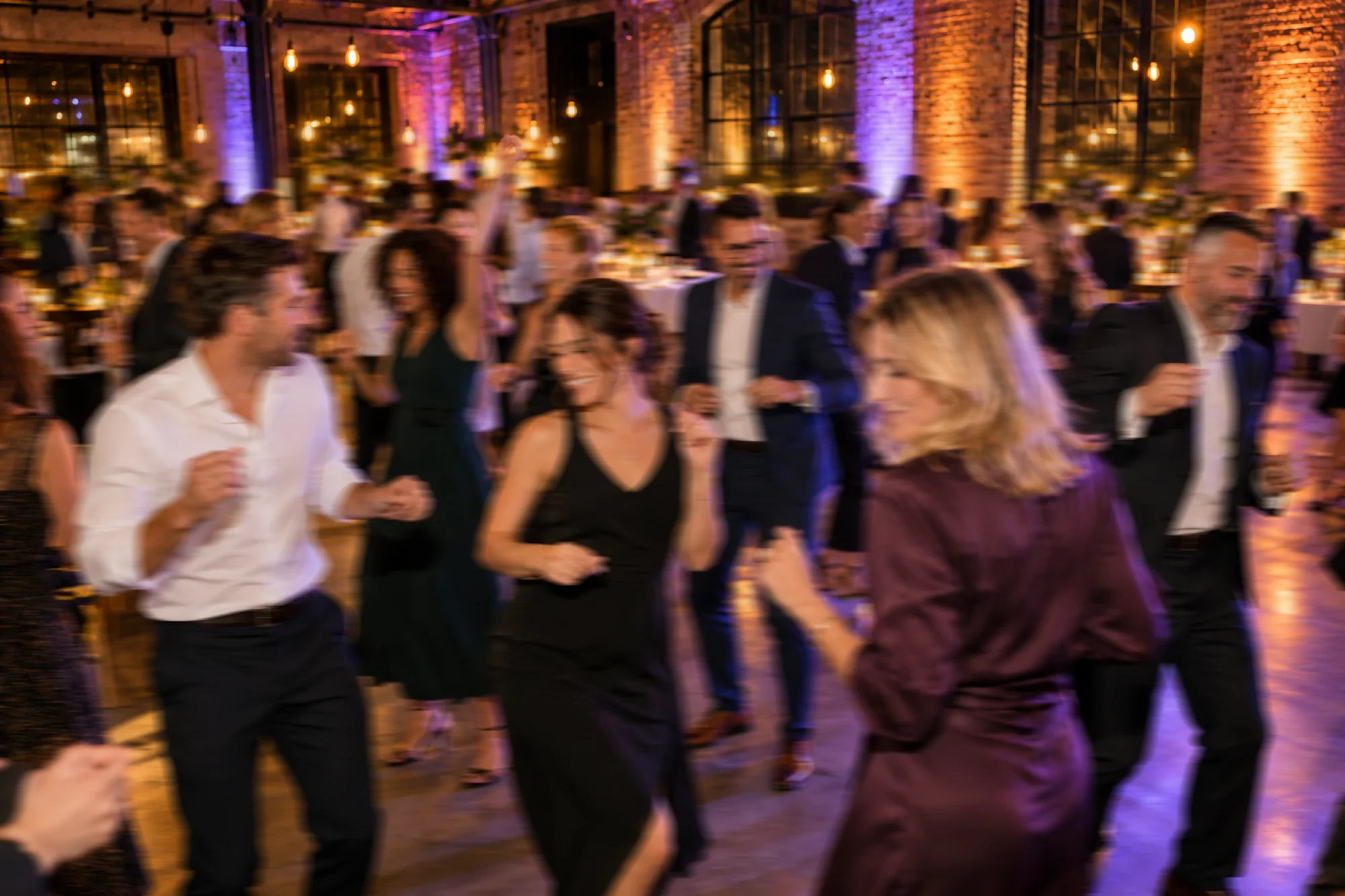 Tanzende Gäste bei einer Firmenveranstaltung am Abend, in Bewegungsunschärfe